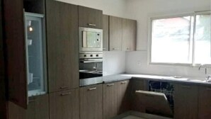 A kitchen with wooden cabinets, a microwave, and a sink. - Magnifique Appartement Meublé Avec Piscine à Pointe Noire (Pointe-Noire)