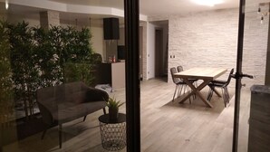 Un salon moderne avec un canapé, une table à manger et des chaises, ainsi qu’une plante en pot.