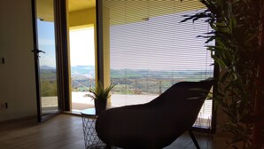 Une pièce avec vue sur un paysage, visible à travers une fenêtre munie de stores.