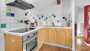 Een moderne keuken met witte kasten, een rvs-fornuis, een magnetron en een spoelbak.