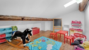 Een kinderspeelkamer met een schommelpaard, een schoolbord en een speelkeuken.