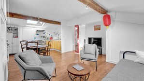 Een moderne woonkamer met een eethoek, houten vloeren en een televisie.