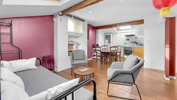 Een moderne woonkamer met een hoge plafond, dakraam en een eethoek met houten meubels.