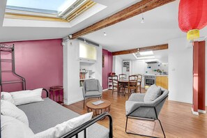 Ein modernes Wohnzimmer mit hoher Decke, Dachfenster und einem Essbereich mit Holzmöbeln.