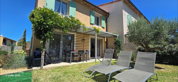A house with a patio, outdoor seating, and a garden.