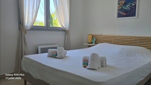 Une chambre d’hôtel avec un grand lit, une table de chevet, une commode, une fenêtre avec des rideaux et une œuvre d’art accrochée au mur.