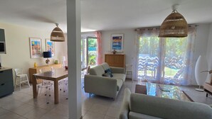 Una cocina moderna con microondas, una mesa de comedor con sillas, un sofá y una lámpara colgante.