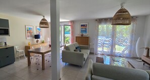 A modern kitchen with a microwave, a dining table with chairs, a sofa, and a hanging light fixture.