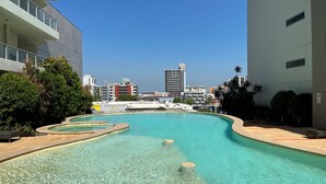 A swimming pool with clear water, surrounded by buildings and greenery. - Darwin City Hotel Suite with Sea View & Balcony  (Darwin City)