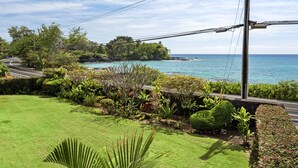 A coastal landscape with a road curving through a well-maintained garden, leading to a beach.