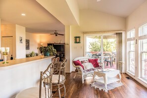 A spacious living area with a dining set, a sofa with cushions, a small table, and a large window with a view of the outdoors. - 4 bedroom Dog Friendly home with community pool (Ocean View)
