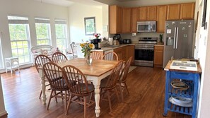 Une cuisine avec des meubles de rangement en bois, un réfrigérateur en acier inoxydable et une table à manger avec des chaises.