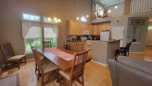 A spacious kitchen with wooden cabinets, a dining area with a table and chairs, and a balcony with a railing.