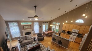 A spacious living area with a fireplace, a dining table, and a kitchen with wooden cabinets and a stove.