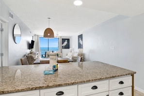 A modern kitchen with a granite countertop, white cabinetry, and a view to the outside.