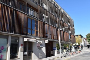 Un bâtiment moderne doté d’une façade en bois, d’une entrée bien visible et d’un espace de stationnement pour vélos.