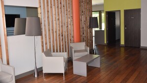 Ein modernes Interieur mit einer Wand aus Holzlamellen, einer großen orangefarbenen Säule und einer Sitzecke mit Couchtisch.