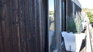 A wooden exterior wall with a sliding glass door and a white planter with tall plants. - Lyon City Retreat near Sâone River (Lyon)