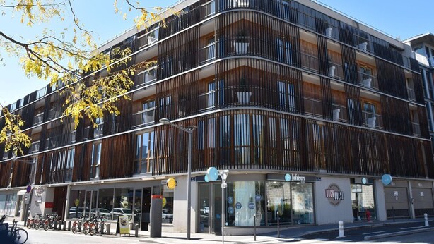 A modern building with a curved facade, multiple balconies, and a ground-level entrance with a sign for 'DUCK OUEST'. - Lyon City Retreat near Sâone River (Lyon)