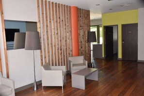 A modern interior with a wooden panel wall, a large orange column, and a seating area with a coffee table.