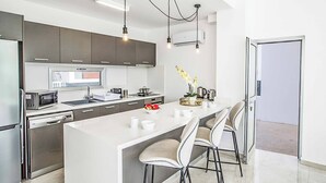 A modern kitchen with a central island, built-in appliances, and pendant lighting.
