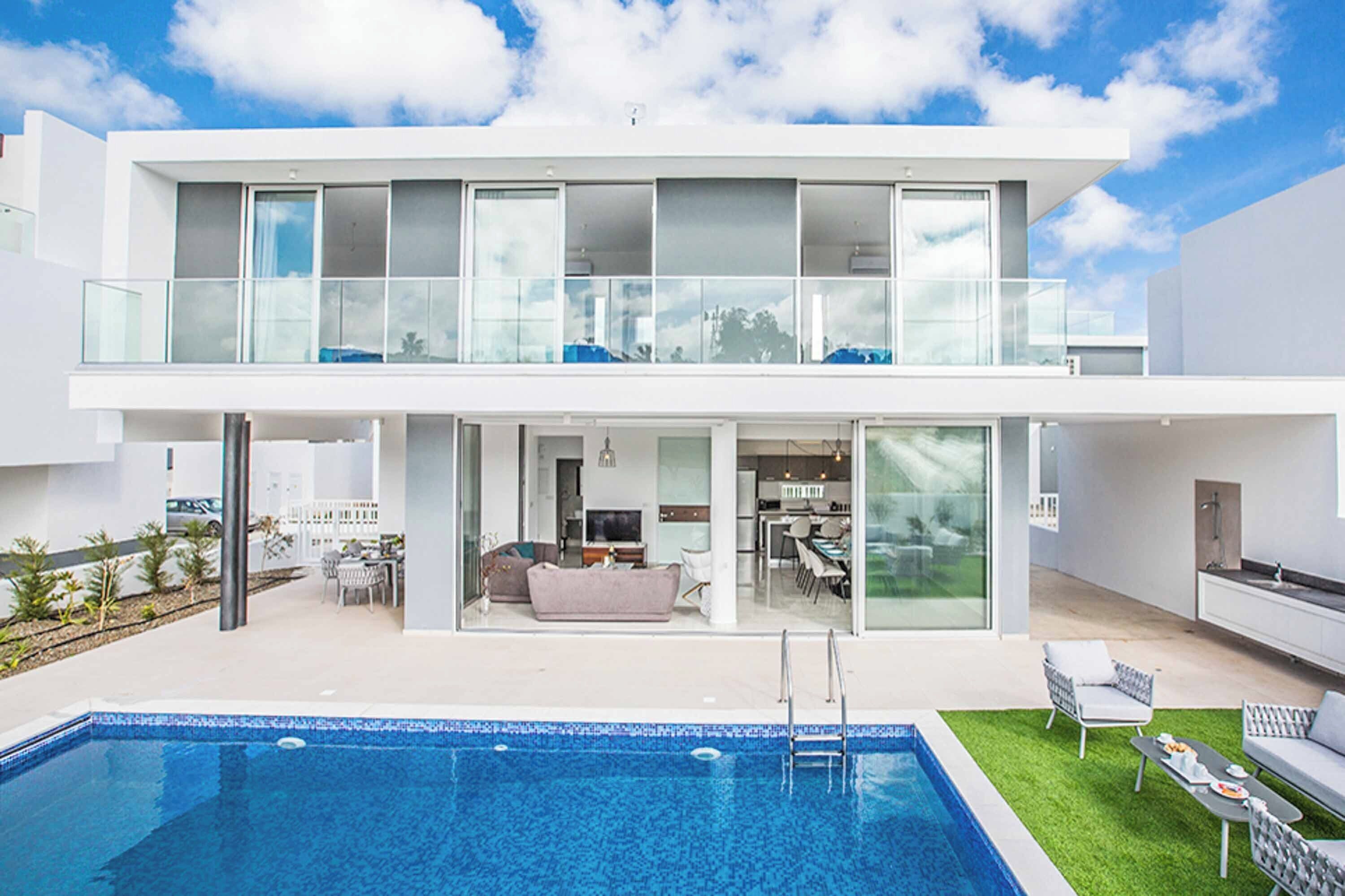 Une maison moderne à deux étages, dotée d’une piscine, d’un balcon et d’un jardin bien entretenu.