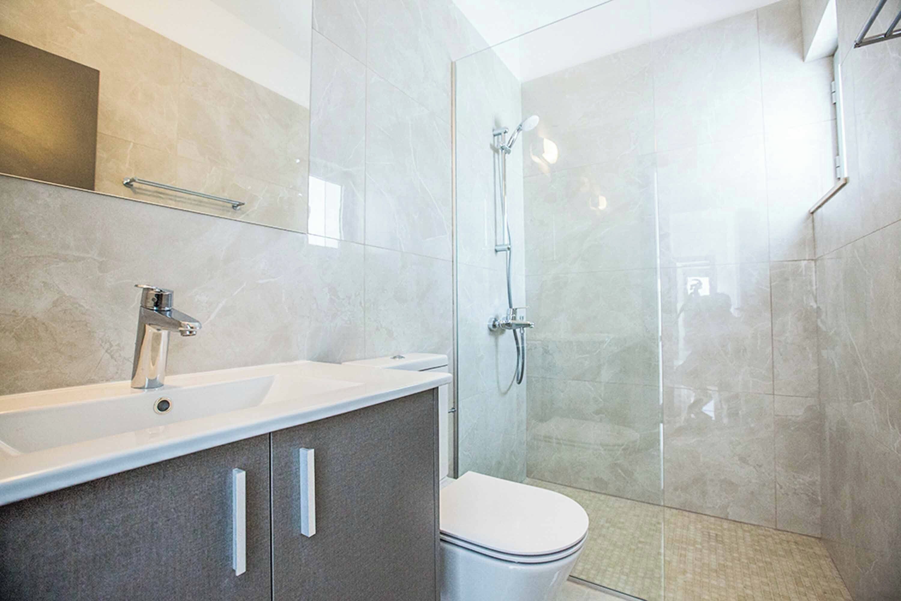Une salle de bain moderne avec une douche à parois de verre, un lavabo blanc et des toilettes.