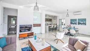A modern living room with a TV, sofa, and dining area.