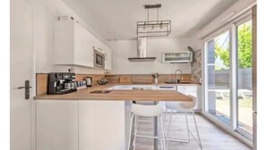 A modern kitchen with white cabinetry, a wooden countertop, a built-in stove, and a large window providing a view of the outdoors.