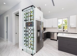 Eine moderne Küche mit Weinkühler, Edelstahlgeräten und einem großen Fenster.