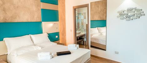 Una habitación de hotel moderna con una cama grande, una mesita de noche, un espejo y un aire acondicionado de pared.