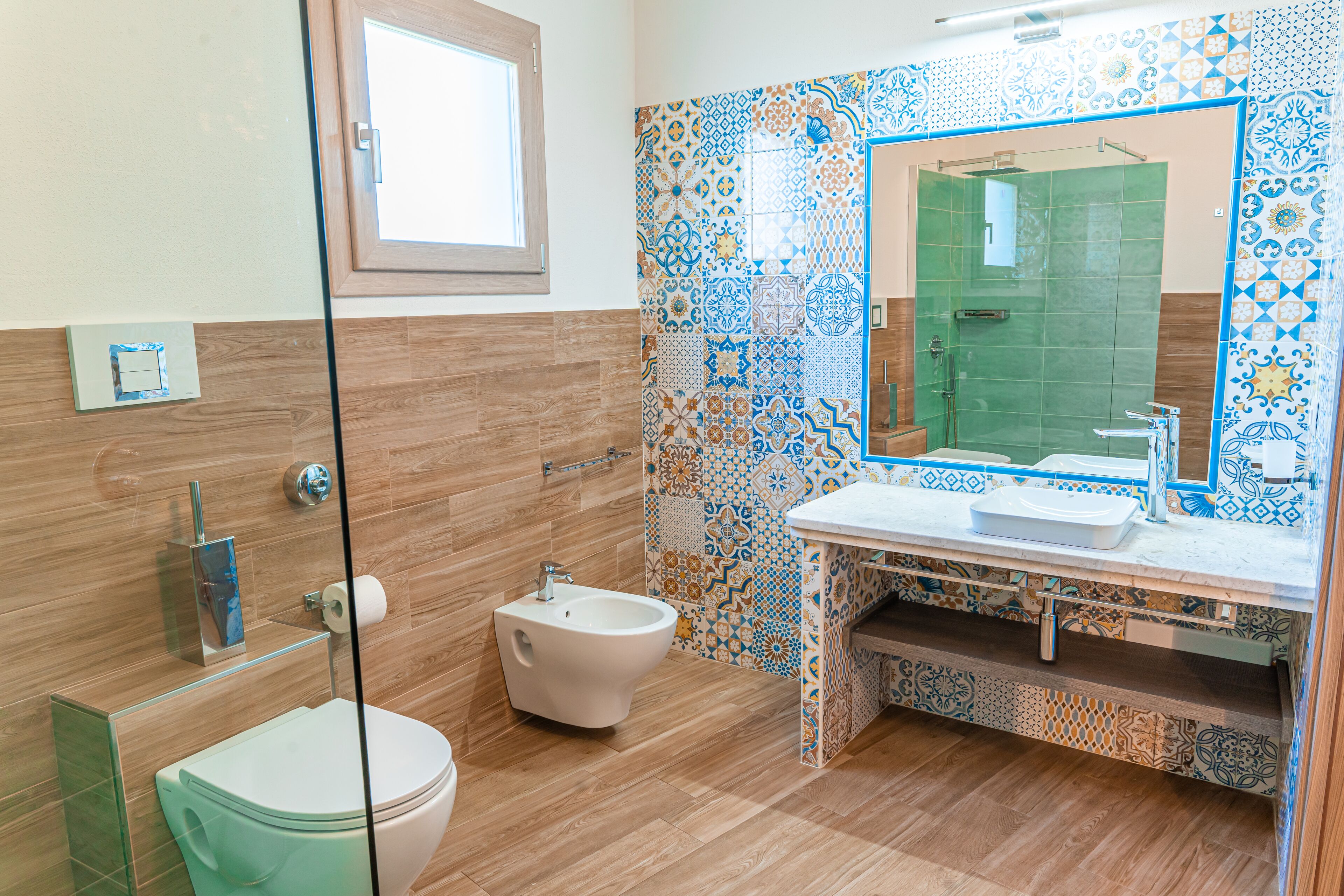 Un baño con cabina de ducha de vidrio, un bidé, un inodoro y un lavabo con espejo.