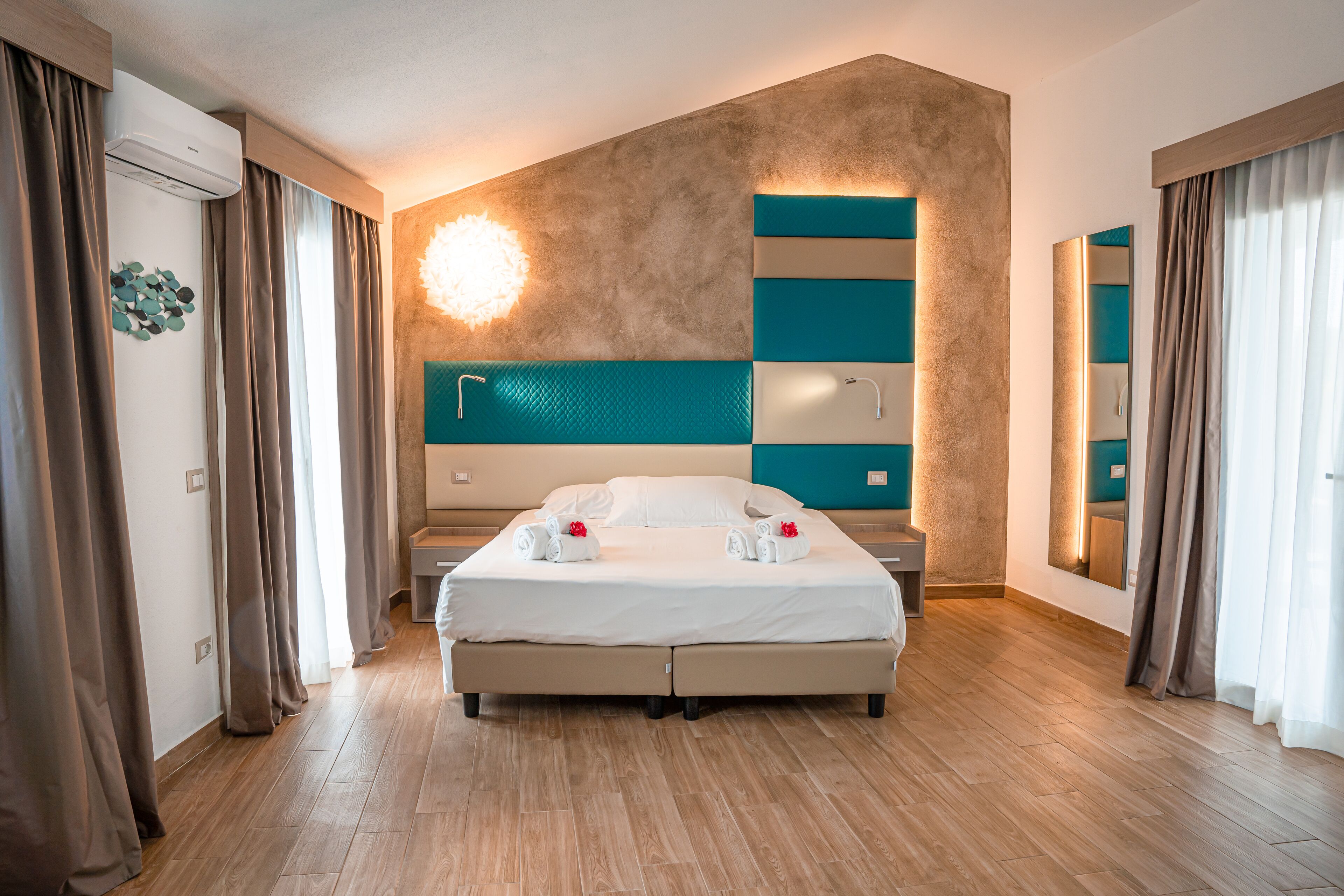 A modern hotel room with a large bed, a built-in desk, and a large mirror.