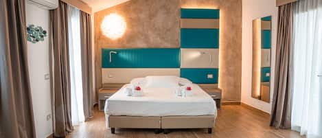 A modern hotel room with a large bed, a built-in desk, and a large mirror.