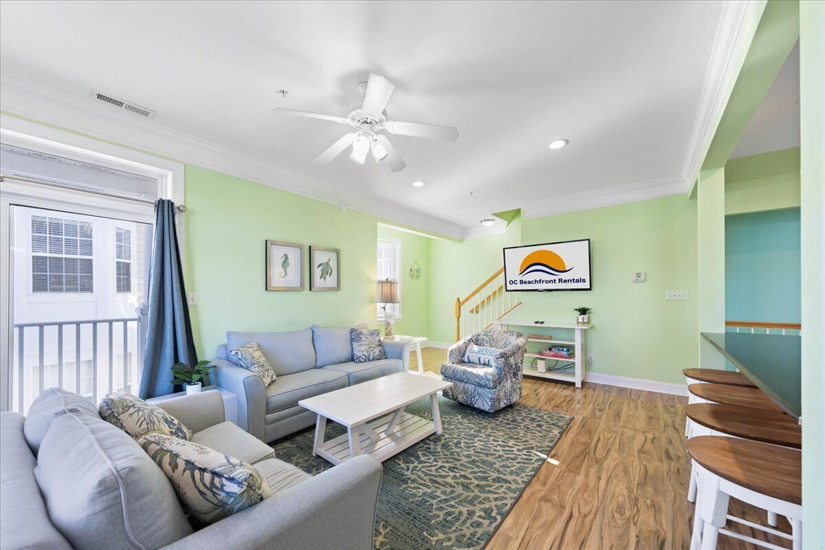 A living room with a sofa, coffee table, and armchairs. There is a staircase leading to another level.