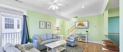 A living room with a sofa, coffee table, and armchairs. There is a staircase leading to another level.