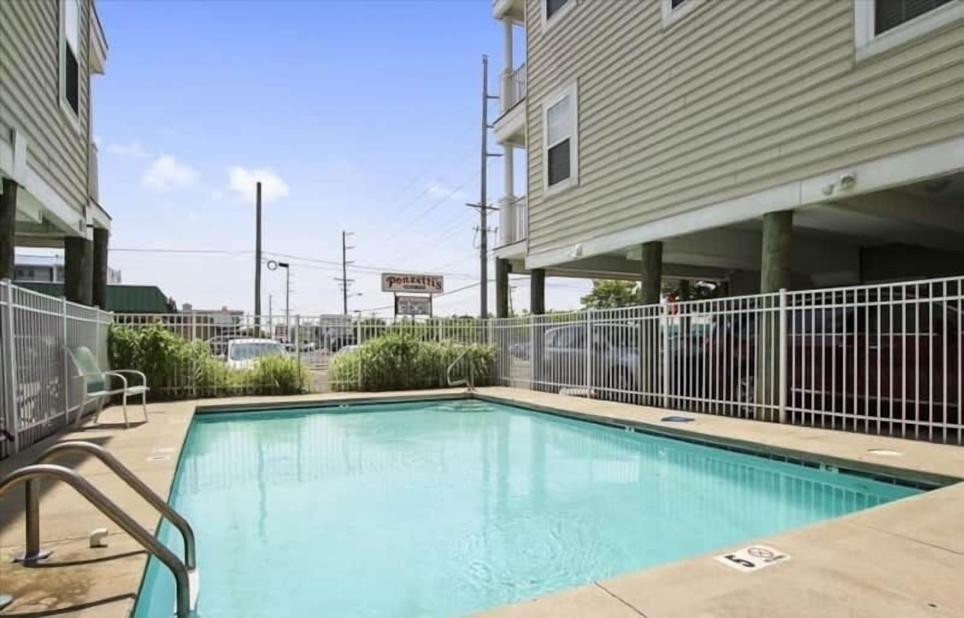 A swimming pool with a metal fence, surrounded by buildings.