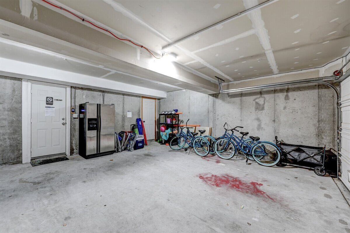Un garage avec des murs en béton, un réfrigérateur et des vélos.