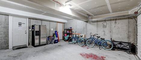 Un garage avec des murs en béton, un réfrigérateur et des vélos.
