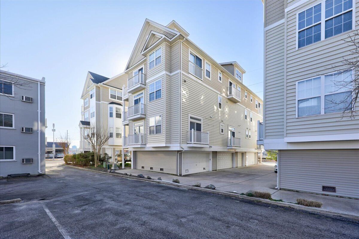 A multi-story residential building with a flat roof, multiple balconies, and a garage.