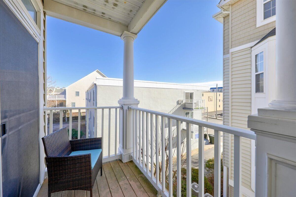 A balcony with a wicker chair and a view of neighboring houses.
