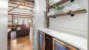 Eine moderne Küche mit Holzbalken, einem eingebauten Backofen und einer Arbeitsplatte mit Regalen, auf denen Handtücher und Pflanzen stehen.