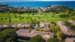 Vista aérea de un complejo turístico con varias construcciones, un campo de golf y vistas al océano.
