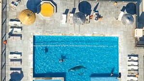 Vista aérea de un área de piscina con varias piscinas, tumbonas y sombrillas.