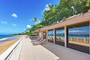 A beachside hotel with a covered patio, lounge chairs, and ocean views.