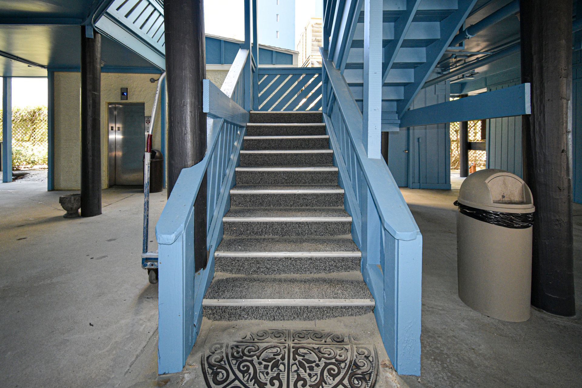 A staircase with blue railings leading to an elevator.