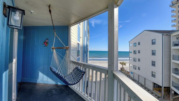 A balcony with a hammock, a view of the beach, and a building with multiple windows. - Seasider 304 - Three Bedrooms, Three Bath Condo in Oceanfront Complex (Garden City Beach)