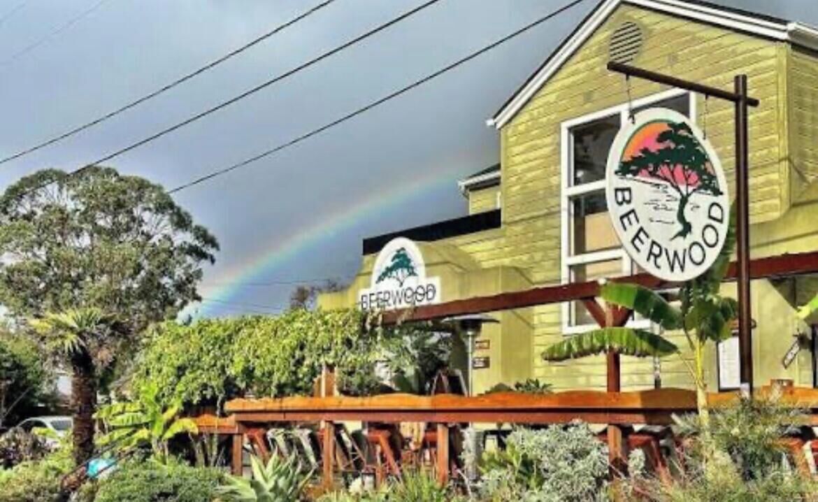 Un edificio con un letrero que dice 'BEERWOOD' y un arcoíris en el fondo.