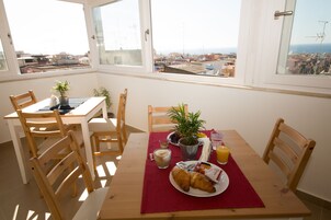 Zona pranzo con tavolo apparecchiato per la colazione, con croissant, succo di frutta e una tazza di caffè.