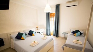 A hotel room with two beds, a desk, a chair, and a small table. - La Balestra B&B (Balestrate)